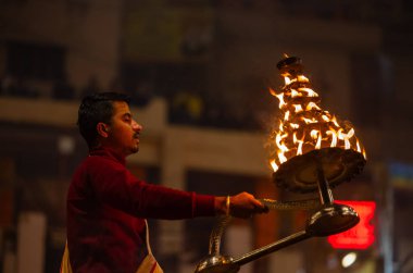 Varanasi, Uttar Pradesh, Hindistan - 18 Ocak 2024: Ganga aarti, Dashashwamedh Ghat geleneksel elbise ve Hindu ayinleri ile Ganj nehri akşam ayini yapan genç rahip portresi.