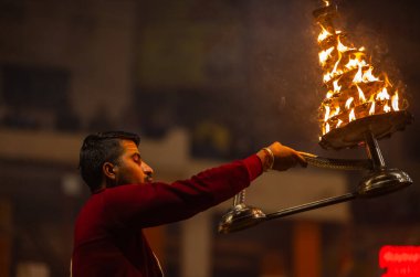 Varanasi, Uttar Pradesh, Hindistan - 18 Ocak 2024: Ganga aarti, Dashashwamedh Ghat geleneksel elbise ve Hindu ayinleri ile Ganj nehri akşam ayini yapan genç rahip portresi.