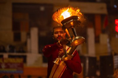 Varanasi, Uttar Pradesh, Hindistan - 18 Ocak 2024: Ganga aarti, Dashashwamedh Ghat geleneksel elbise ve Hindu ayinleri ile Ganj nehri akşam ayini yapan genç rahip portresi.