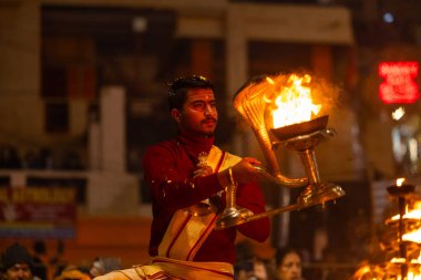 Varanasi, Uttar Pradesh, Hindistan - 18 Ocak 2024: Ganga aarti, Dashashwamedh Ghat geleneksel elbise ve Hindu ayinleri ile Ganj nehri akşam ayini yapan genç rahip portresi.