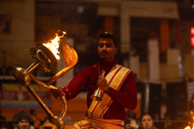 Varanasi, Uttar Pradesh, Hindistan - 18 Ocak 2024: Ganga aarti, Dashashwamedh Ghat geleneksel elbise ve Hindu ayinleri ile Ganj nehri akşam ayini yapan genç rahip portresi.