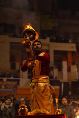 Varanasi, Uttar Pradesh, Hindistan - 18 Ocak 2024: Ganga aarti, Dashashwamedh Ghat geleneksel elbise ve Hindu ayinleri ile Ganj nehri akşam ayini yapan genç rahip portresi.