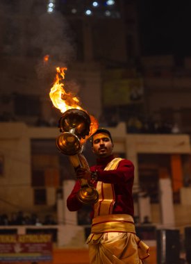 Varanasi, Uttar Pradesh, Hindistan - 18 Ocak 2024: Ganga aarti, Dashashwamedh Ghat geleneksel elbise ve Hindu ayinleri ile Ganj nehri akşam ayini yapan genç rahip portresi.