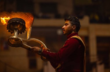 Varanasi, Uttar Pradesh, Hindistan - 18 Ocak 2024: Ganga aarti, Dashashwamedh Ghat geleneksel elbise ve Hindu ayinleri ile Ganj nehri akşam ayini yapan genç rahip portresi.