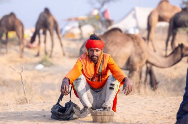 Pushkar, Rajasthan, Hindistan - 24 Kasım 2023: İtme arabası fuarı sırasında yılanlı kırmızı türban kutulu genç bir erkek yılan portresi. 