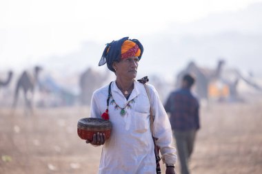 Pushkar, Rajasthan, Hindistan - 24 Kasım 2023: Renkli türban kutusunda yılan taşıyan erkek yılan portresi. 