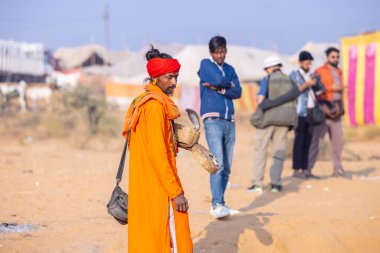 Pushkar, Rajasthan, Hindistan - 24 Kasım 2023: İtme arabası fuarı sırasında kobra yılanlı kırmızı türban kutulu genç bir erkek yılan portresi. 