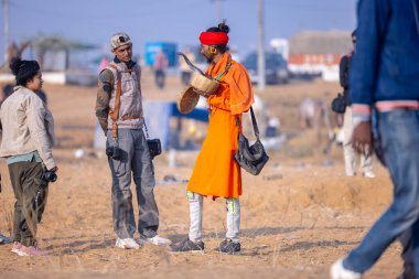 Pushkar, Rajasthan, Hindistan - 24 Kasım 2023: İtme arabası fuarı sırasında kobra yılanlı kırmızı türban kutulu genç bir erkek yılan portresi. 