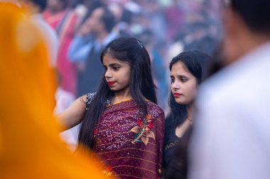 Gaziabad, Uttar Pradesh, Hindistan - 19 Kasım 2023: Nehir kıyısına doğru yürüyen bir grup Hintli aile ile birlikte etnik renkli giysiler içinde Chhas puja ayinlerini gerçekleştirmek için.