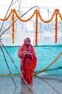 Gaziabad, Uttar Pradesh, Hindistan - 19 Kasım 2023: Hintli Hintli kadın dindar Chhas Puja portresi, gün batımında güneş tanrısı güneşe ibadet etmek için nehirde duran chhas puja ayinlerini gerçekleştiriyor..