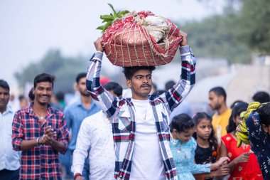 Gaziabad, Uttar Pradesh, Hindistan - 19 Kasım 2023: Nehir kıyısına doğru yürüyen bir grup Hintli aile ile birlikte etnik renkli giysiler içinde Chhas puja ayinlerini gerçekleştirmek için.