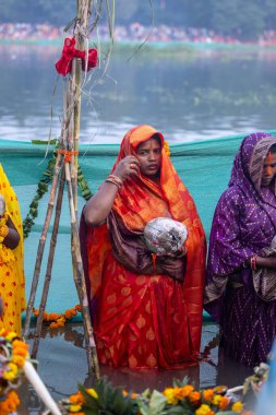 Gaziabad, Uttar Pradesh, Hindistan - 19 Kasım 2023: Chhas Puja, Hintli Hintli kadın dindarların portresi, gün batımında güneş tanrısı güneşe ibadet etmek için nehirde durarak Chhas puja ayini yapıyorlar..