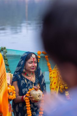 Ghaziabad, Uttar Pradesh, India - November 19 2023: Chhath Puja, Portrait of indian hindu female devotees performing rituals of chhath puja with standing in river to worship lord sun during sunset. clipart