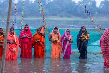 Gaziabad, Uttar Pradesh, Hindistan - 19 Kasım 2023: Chhas Puja, Hintli Hintli bir grup kadın günbatımında tanrıya ibadet etmek için nehirde duran Chhas puja ayinlerini gerçekleştiriyor..