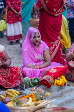 Gaziabad, Uttar Pradesh, Hindistan - 19 Kasım 2023: Chhas Puja, bir grup Hintli kadın geleneksel etnik kıyafetlerle chhas puja ayinlerini gerçekleştirmek için zemin üzerinde oturuyorlar.