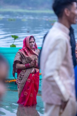 Gaziabad, Uttar Pradesh, Hindistan - 19 Kasım 2023: Chhas Puja, Hintli kadın dindar Chhas puja 'nın portresi gün batımında güneş tanrısı güneşe ibadet etmek için nehirde durarak ritüellerini gerçekleştiriyor..