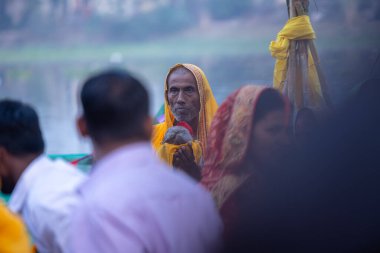 Gaziabad, Uttar Pradesh, Hindistan - 19 Kasım 2023: Chhas Puja, Hintli Hintli erkek dindar portresi Chhas puja ritüellerini gerçekleştiriyor ve gün batımında Lord Sun 'a ibadet etmek için nehirde duruyor..