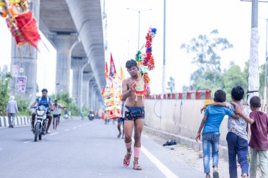 Gaziabad, Uttar Pradesh, Hindistan - 31 Temmuz 2024: Sawan Shivratri sırasında çıplak ayakla Kanwar Yatra 'yı seslendiren Hindu hacıların portresi ve Hindu tanrısı Shiva' ya ibadet etmek için kutsal Ganga suyu taşımak.