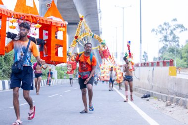 Gaziabad, Uttar Pradesh, Hindistan - 31 Temmuz 2024: Sawan Shivratri sırasında çıplak ayakla Kanwar Yatra 'yı seslendiren Hindu hacıların portresi ve Hindu tanrısı Shiva' ya ibadet etmek için kutsal Ganga suyu taşımak.