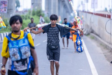 Ghaziabad, Uttar Pradesh, India - July 31 2024: Portrait of Hindu pilgrims performing Kanwar Yatra barefoot during Sawan Shivratri and carrying holy ganga water to worship Hindu god Shiva with rituals. clipart