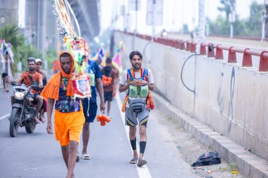 Gaziabad, Uttar Pradesh, Hindistan - 31 Temmuz 2024: Sawan Shivratri sırasında çıplak ayakla Kanwar Yatra 'yı seslendiren Hindu hacıların portresi ve Hindu tanrısı Shiva' ya ibadet etmek için kutsal Ganga suyu taşımak.