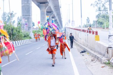 Gaziabad, Uttar Pradesh, Hindistan - 31 Temmuz 2024: Sawan Shivratri sırasında çıplak ayakla Kanwar Yatra 'yı seslendiren Hindu hacıların portresi ve Hindu tanrısı Shiva' ya ibadet etmek için kutsal Ganga suyu taşımak.