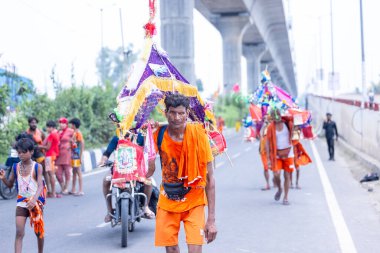 Gaziabad, Uttar Pradesh, Hindistan - 31 Temmuz 2024: Sawan Shivratri sırasında çıplak ayakla Kanwar Yatra 'yı seslendiren Hindu hacıların portresi ve Hindu tanrısı Shiva' ya ibadet etmek için kutsal Ganga suyu taşımak.