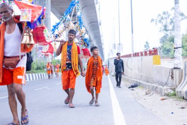 Gaziabad, Uttar Pradesh, Hindistan - 31 Temmuz 2024: Sawan Shivratri sırasında çıplak ayakla Kanwar Yatra 'yı seslendiren Hindu hacıların portresi ve Hindu tanrısı Shiva' ya ibadet etmek için kutsal Ganga suyu taşımak.