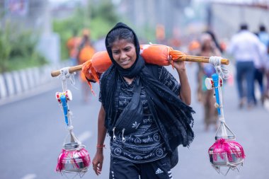 Gaziabad, Uttar Pradesh, Hindistan - 31 Temmuz 2024: Sawan Shivratri sırasında çıplak ayakla Kanwar Yatra 'yı seslendiren Hindu kadın hacıların portresi ve Hindu tanrısı Shiva' ya ibadet etmek için kutsal Ganga suyu taşımak.