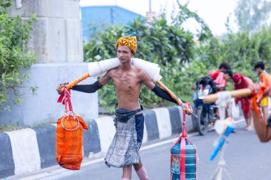 Gaziabad, Uttar Pradesh, Hindistan - 31 Temmuz 2024: Sawan Shivratri sırasında çıplak ayakla Kanwar Yatra 'yı seslendiren Hindu hacıların portresi ve Hindu tanrısı Shiva' ya ibadet etmek için kutsal Ganga suyu taşımak.