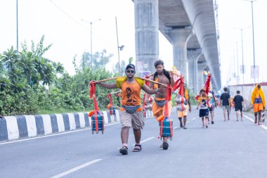 Gaziabad, Uttar Pradesh, Hindistan - 31 Temmuz 2024: Sawan Shivratri sırasında çıplak ayakla Kanwar Yatra 'yı seslendiren Hindu hacıların portresi ve Hindu tanrısı Shiva' ya ibadet etmek için kutsal Ganga suyu taşımak.