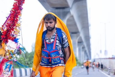 Gaziabad, Uttar Pradesh, Hindistan - 31 Temmuz 2024: Sawan Shivratri sırasında çıplak ayakla Kanwar Yatra 'yı seslendiren Hindu hacı portresi ve Hindu tanrısı Shiva' ya ibadet etmek için kutsal Ganga suyu taşımak.