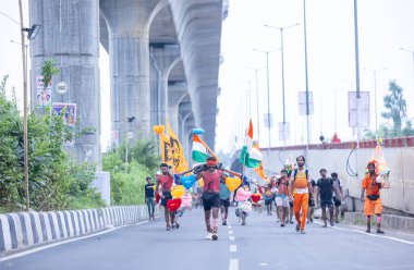 Gaziabad, Uttar Pradesh, Hindistan - 31 Temmuz 2024: Sawan Shivratri sırasında çıplak ayakla Kanwar Yatra 'yı seslendiren Hindu hacıların portresi ve Hindu tanrısı Shiva' ya ibadet etmek için kutsal Ganga suyu taşımak.