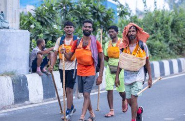 Gaziabad, Uttar Pradesh, Hindistan - 31 Temmuz 2024: Sawan Shivratri sırasında çıplak ayakla Kanwar Yatra 'yı seslendiren Hindu hacıların portresi ve Hindu tanrısı Shiva' ya ibadet etmek için kutsal Ganga suyu taşımak.