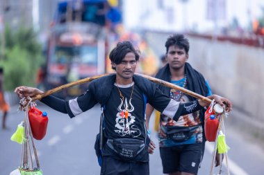 Gaziabad, Uttar Pradesh, Hindistan - 31 Temmuz 2024: Sawan Shivratri sırasında çıplak ayakla Kanwar Yatra 'yı seslendiren Hindu hacıların portresi ve Hindu tanrısı Shiva' ya ibadet etmek için kutsal Ganga suyu taşımak.