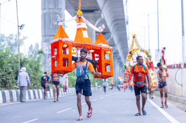 Gaziabad, Uttar Pradesh, Hindistan - 31 Temmuz 2024: Sawan Shivratri sırasında çıplak ayakla Kanwar Yatra 'yı seslendiren Hindu hacıların portresi ve Hindu tanrısı Shiva' ya ibadet etmek için kutsal Ganga suyu taşımak.