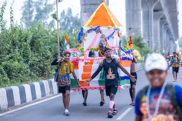 Gaziabad, Uttar Pradesh, Hindistan - 31 Temmuz 2024: Sawan Shivratri sırasında çıplak ayakla Kanwar Yatra 'yı seslendiren Hindu hacıların portresi ve Hindu tanrısı Shiva' ya ibadet etmek için kutsal Ganga suyu taşımak.