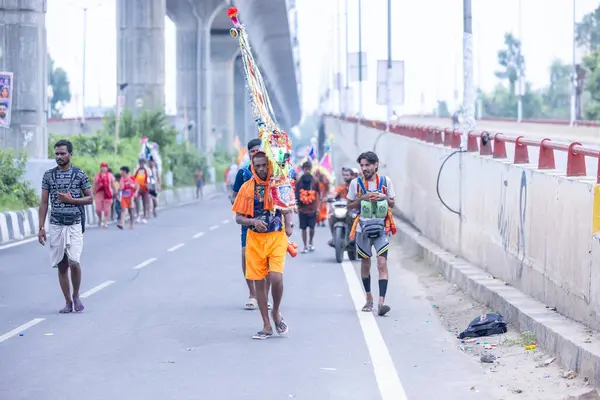 Gaziabad, Uttar Pradesh, Hindistan - 31 Temmuz 2024: Sawan Shivratri sırasında çıplak ayakla Kanwar Yatra 'yı seslendiren Hindu hacıların portresi ve Hindu tanrısı Shiva' ya ibadet etmek için kutsal Ganga suyu taşımak.