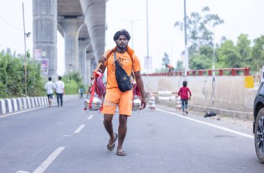 Gaziabad, Uttar Pradesh, Hindistan - 31 Temmuz 2024: Sawan Shivratri sırasında çıplak ayakla Kanwar Yatra 'yı seslendiren Hindu hacı portresi ve Hindu tanrısı Shiva' ya ibadet etmek için kutsal Ganga suyu taşımak.