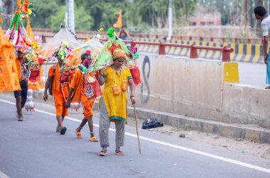 Gaziabad, Uttar Pradesh, Hindistan - 31 Temmuz 2024: Sawan Shivratri sırasında çıplak ayakla Kanwar Yatra 'yı seslendiren Hindu hacıların portresi ve Hindu tanrısı Shiva' ya ibadet etmek için kutsal Ganga suyu taşımak.