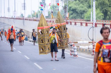 Gaziabad, Uttar Pradesh, Hindistan - 31 Temmuz 2024: Sawan Shivratri sırasında çıplak ayakla Kanwar Yatra 'yı seslendiren Hindu hacıların portresi ve Hindu tanrısı Shiva' ya ibadet etmek için kutsal Ganga suyu taşımak.