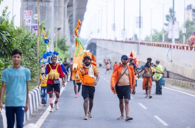 Gaziabad, Uttar Pradesh, Hindistan - 31 Temmuz 2024: Sawan Shivratri sırasında çıplak ayakla Kanwar Yatra 'yı seslendiren Hindu hacıların portresi ve Hindu tanrısı Shiva' ya ibadet etmek için kutsal Ganga suyu taşımak.