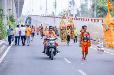 Gaziabad, Uttar Pradesh, Hindistan - 31 Temmuz 2024: Hindu hacıların Sawan Shivratri sırasında yürüyerek Kanwar Yatra 'yı sahneleyen ve Hindu tanrısı Shiva' ya ibadet etmek için kutsal Ganga suyu taşıyan portresi.