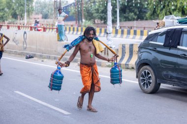 Gaziabad, Uttar Pradesh, Hindistan - 31 Temmuz 2024: Sawan Shivratri sırasında çıplak ayakla Kanwar Yatra 'yı seslendiren Hindu hacı portresi ve Hindu tanrısı Shiva' ya ibadet etmek için kutsal Ganga suyu taşımak.