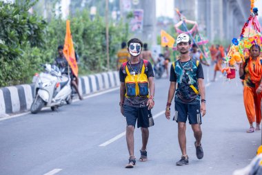 Gaziabad, Uttar Pradesh, Hindistan - 31 Temmuz 2024: Sawan Shivratri sırasında çıplak ayakla Kanwar Yatra 'yı seslendiren Hindu hacıların portresi ve Hindu tanrısı Shiva' ya ibadet etmek için kutsal Ganga suyu taşımak.