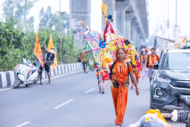 Gaziabad, Uttar Pradesh, Hindistan - 31 Temmuz 2024: Sawan Shivratri sırasında çıplak ayakla Kanwar Yatra 'yı seslendiren Hindu kadın hacıların portresi ve Hindu tanrısı Shiva' ya ibadet etmek için kutsal Ganga suyu taşımak.