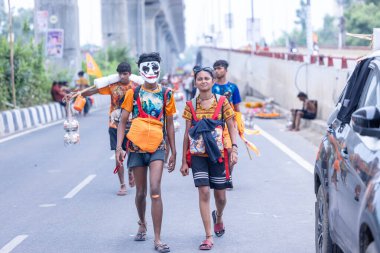 Gaziabad, Uttar Pradesh, Hindistan - 31 Temmuz 2024: Sawan Shivratri sırasında çıplak ayakla Kanwar Yatra 'yı seslendiren Hindu hacıların portresi ve Hindu tanrısı Shiva' ya ibadet etmek için kutsal Ganga suyu taşımak.