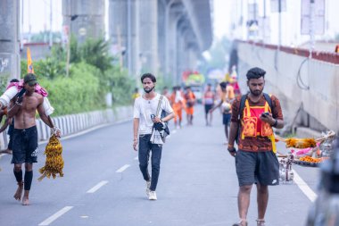 Gaziabad, Uttar Pradesh, Hindistan - 31 Temmuz 2024: Sawan Shivratri sırasında çıplak ayakla Kanwar Yatra 'yı seslendiren Hindu hacıların portresi ve Hindu tanrısı Shiva' ya ibadet etmek için kutsal Ganga suyu taşımak.