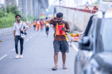 Gaziabad, Uttar Pradesh, Hindistan - 31 Temmuz 2024: Sawan Shivratri sırasında çıplak ayakla Kanwar Yatra 'yı seslendiren Hindu hacıların portresi ve Hindu tanrısı Shiva' ya ibadet etmek için kutsal Ganga suyu taşımak.
