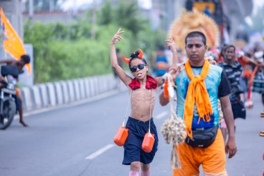 Gaziabad, Uttar Pradesh, Hindistan - 31 Temmuz 2024: Sawan Shivratri sırasında çıplak ayakla Kanwar Yatra 'yı seslendiren Hindu hacıların portresi ve Hindu tanrısı Shiva' ya ibadet etmek için kutsal Ganga suyu taşımak.